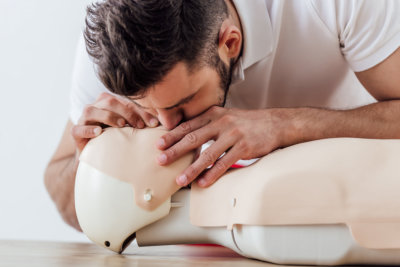 man using mouth to mouth technique on dummy during cpr training